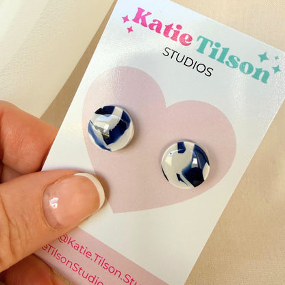 Pair of blue and white swirled design stud earrings held on a Katie Tilson Studios card.