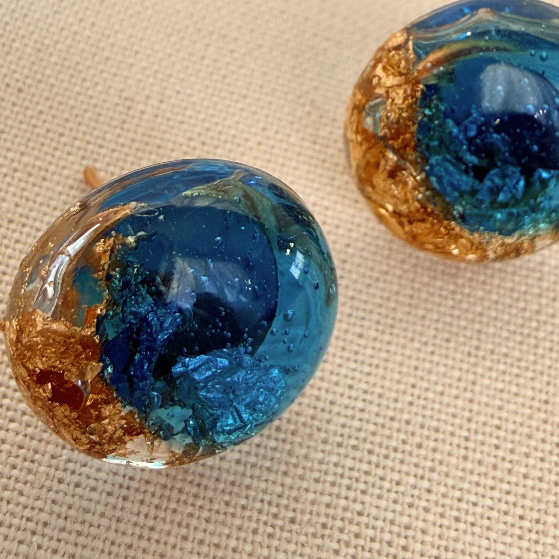 Close up of Ocean Pebble Australian handmade earrings in translucent teal with gold leaf.