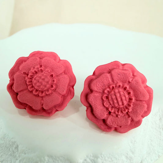 Peach Blossom Australian handmade stud earrings in blush colour floral shape resting on a white stone surface against a beige background.