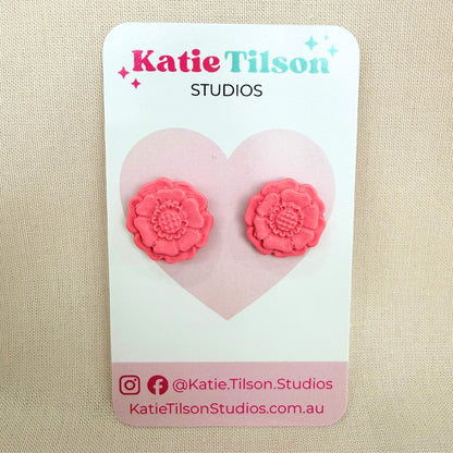 Blush coloured flower shaped stud earrings on a Katie Tilson Studios branded earring card resting against a beige background.