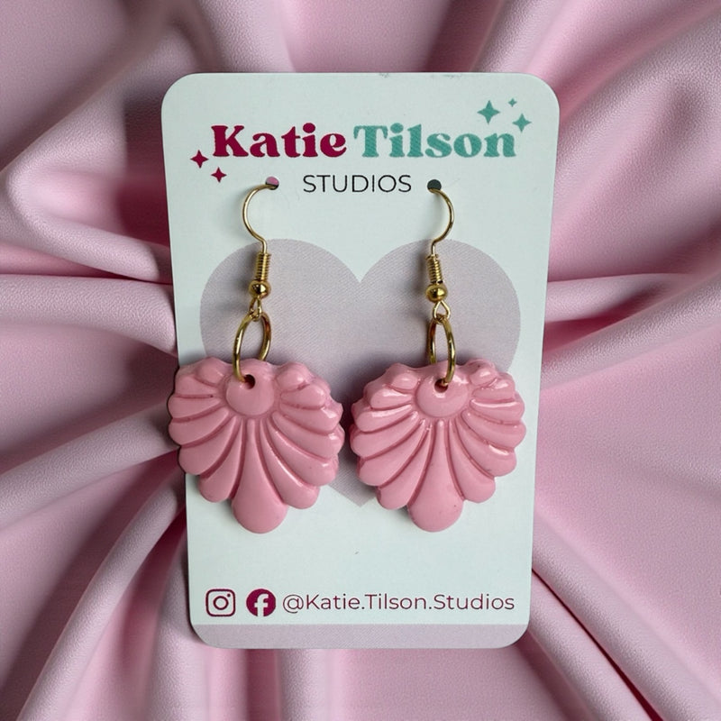 Pink shell-shaped earrings on a Katie Tilson Studios card with a white background