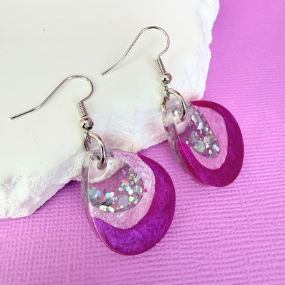 Pink Glow Australian handmade resin dangle earrings in shown in small size resting against a white rock.