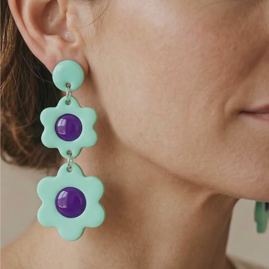 Close up video showing woman wearing mint bloom dangle earrings.