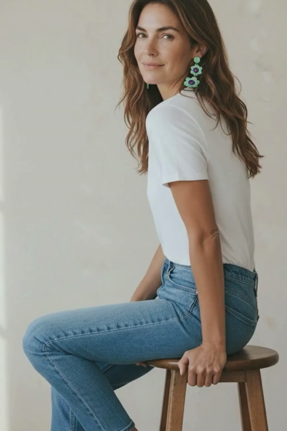 Video of a woman wearing mint and purple flower statement earrings and a casual blue jeans and white t-shirt outfit.
