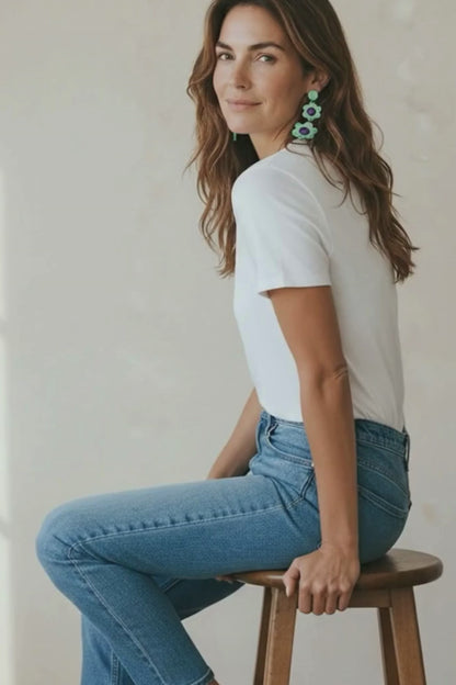Video of a woman wearing mint and purple flower statement earrings and a casual blue jeans and white t-shirt outfit.