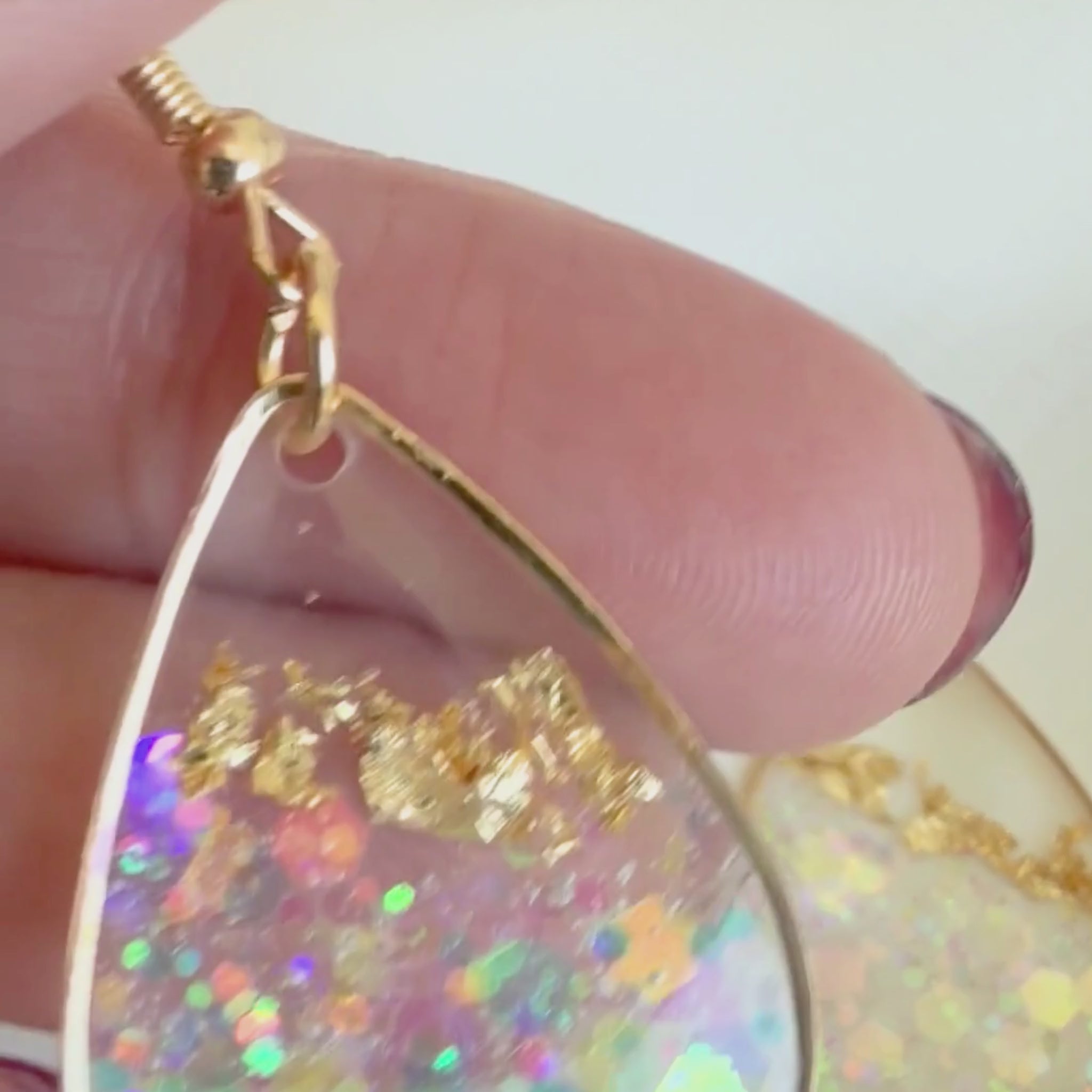 Video of Golden Light handmade earrings being held to show resin detail and shimmer.