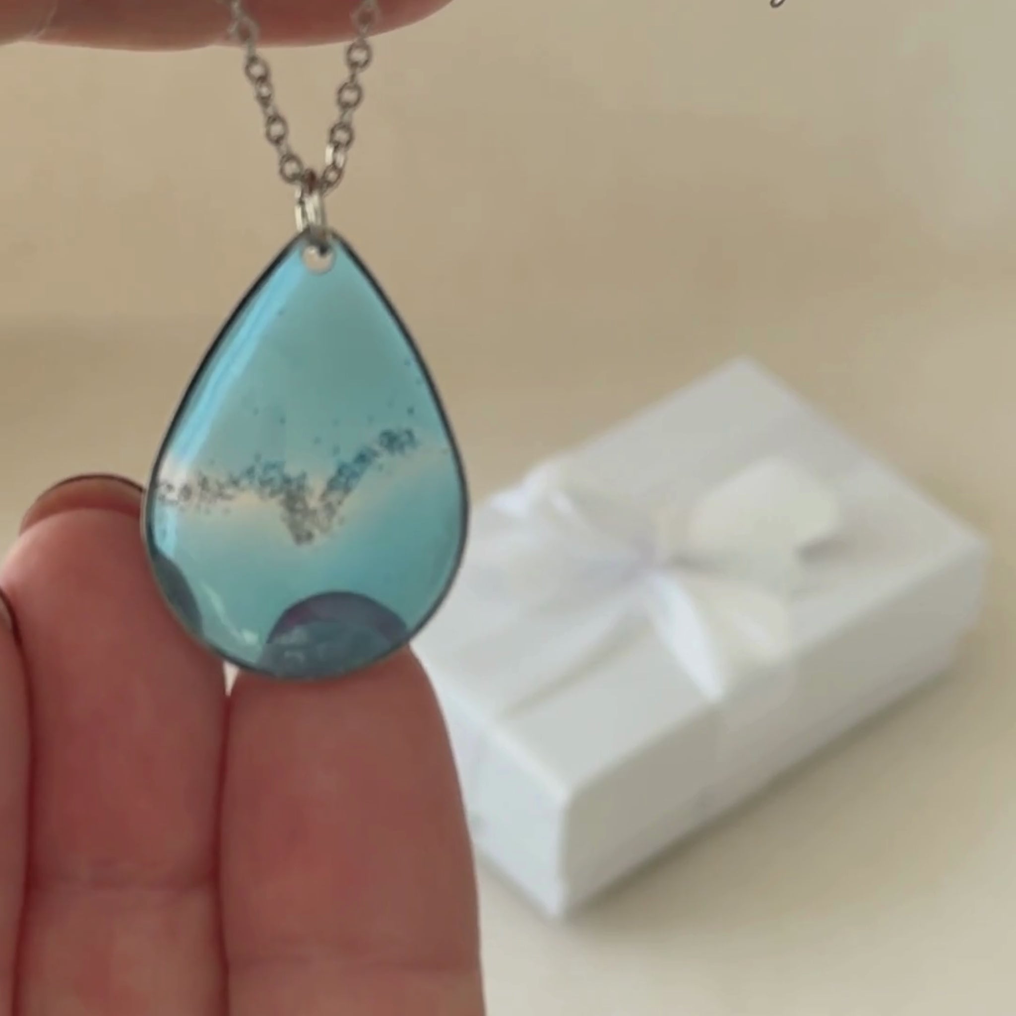 Coastal Glow handmade necklace being held in hands to show resin details.