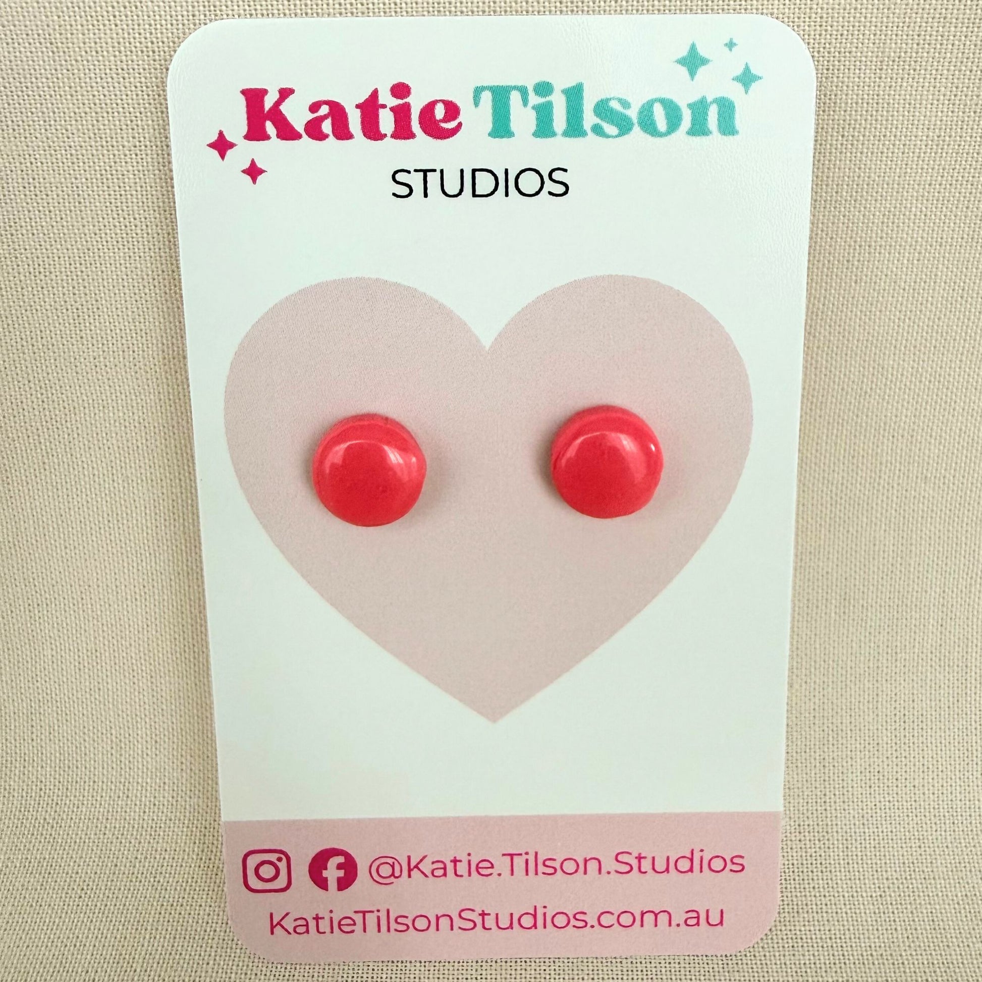 Pink circular stud earrings on a Katie Tilson Studios card against a beige background.