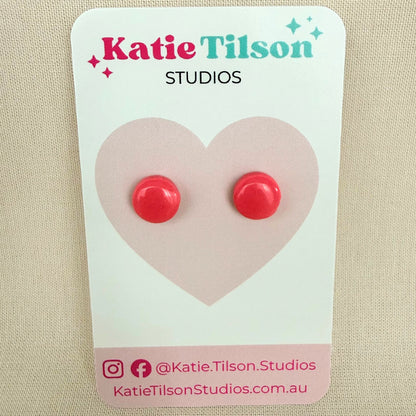 Pink circular stud earrings on a Katie Tilson Studios card against a beige background.