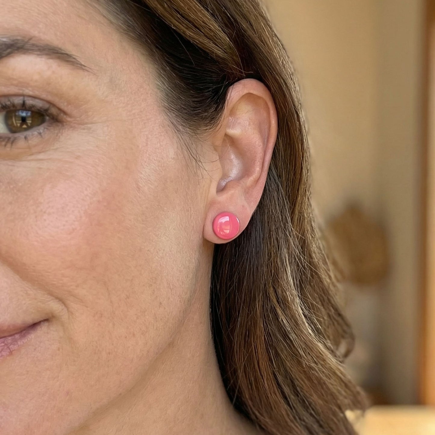 Close-up of a woman wearing pink stud earrings with a blurred background.