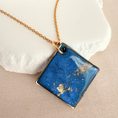 Shine On teal colour handmade pendant necklace in diamond shape with gold leaf detail and glossy finish hanging from gold toned chain.