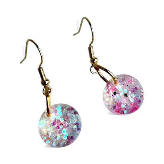 Pink and white iridescent glitter resin circle earrings with gold nickel-free hooks.