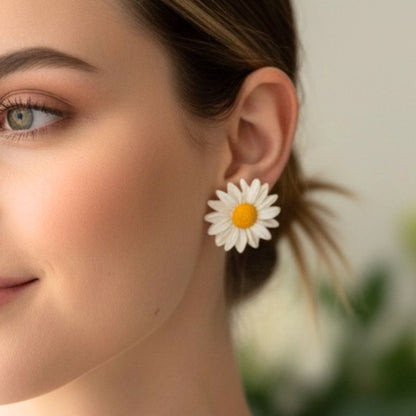 Close-up of a woman wearing Sunny Daisy Australian handmade stud earrings in a daisy flower design against a blurred background. 