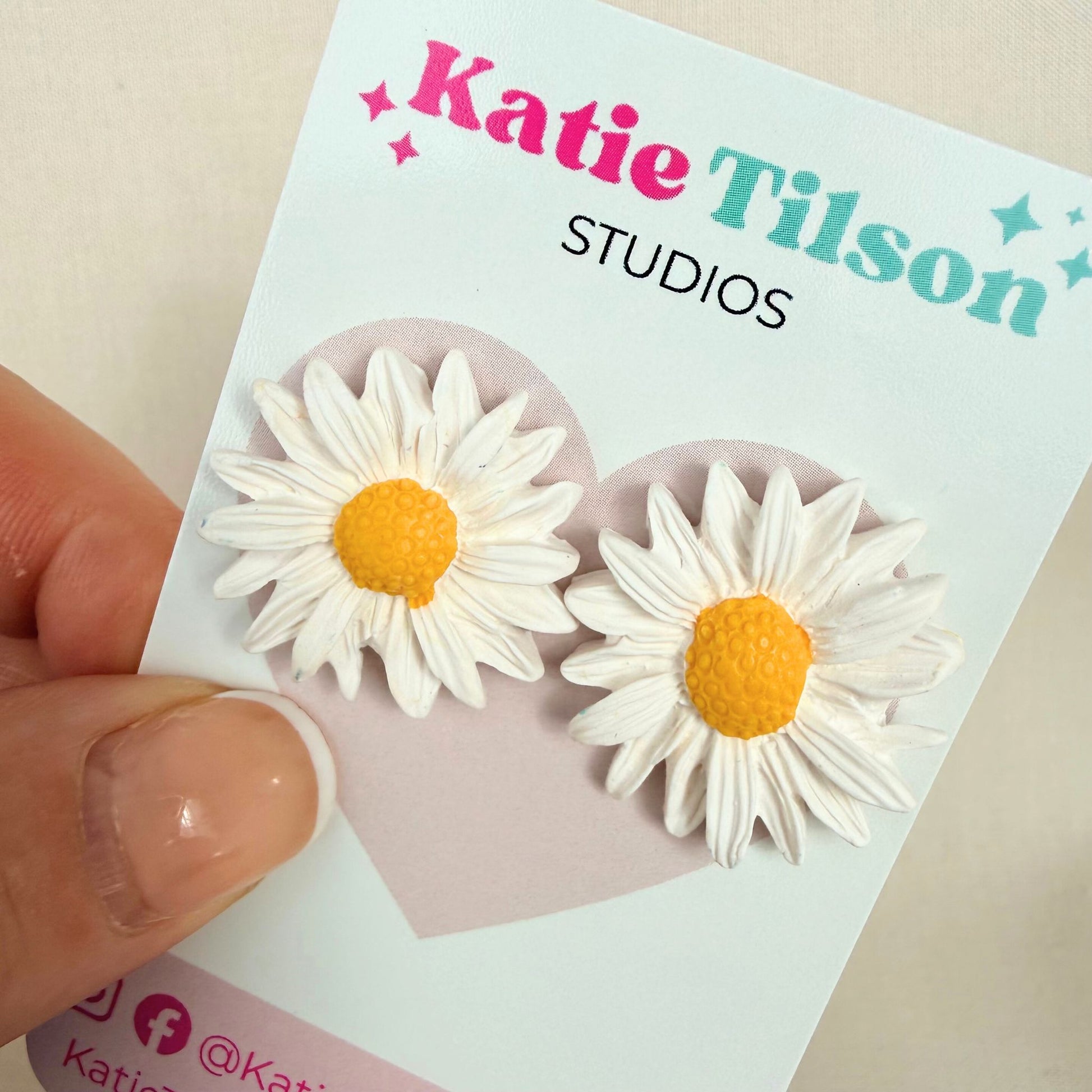 Sunny Daisy Australian handmade stud earrings on a Katie Tilson Studios branded earring card held by a hand.