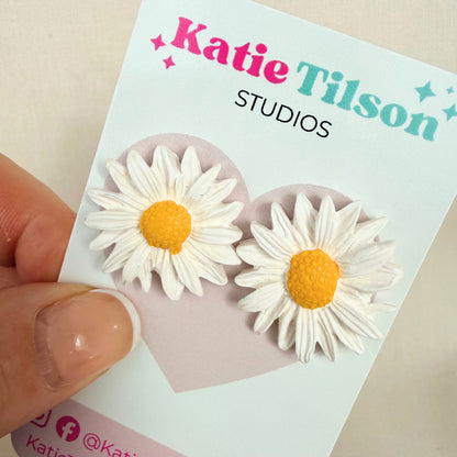 Sunny Daisy Australian handmade stud earrings on a Katie Tilson Studios branded earring card held by a hand.