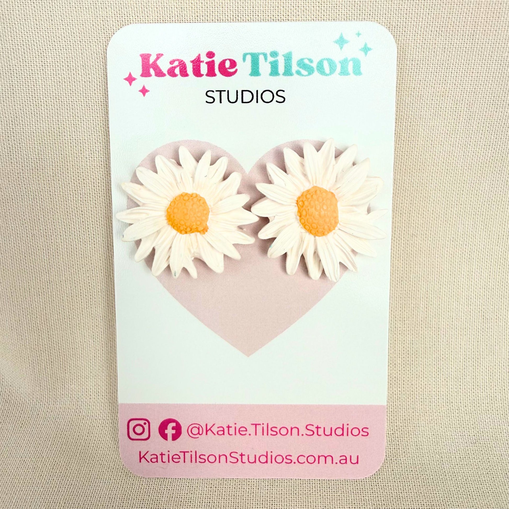 Sunny Daisy Australian handmade stud earrings on a Katie Tilson Studios branded earring card resting on a beige fabric background.