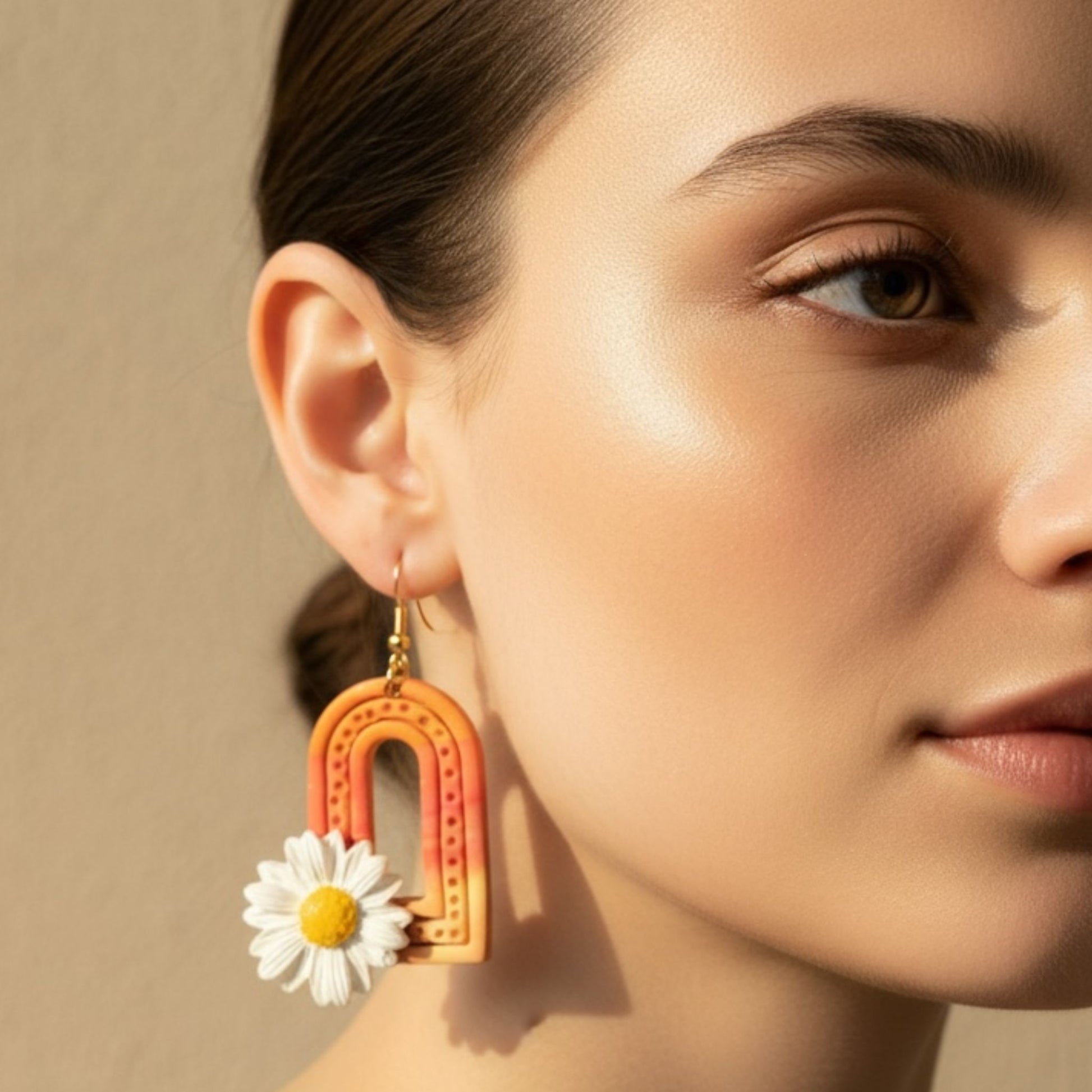 Close-up of a woman wearing Sunrise Daisy Arches colorful statement dangle earring with a daisy design.