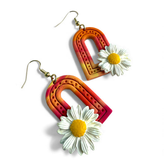 Gradient pink, orange and yellow polymer clay arch earrings with daisy detail.