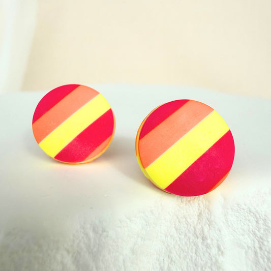 Sunset Pop handmade stud earrings in a red, orange and yellow striped design resting on a white surface.