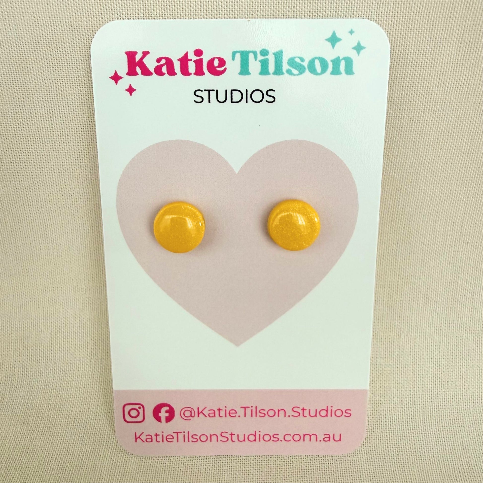 Yellow circular stud earrings on a Katie Tilson Studios card with a beige background.
