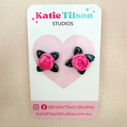 Pink rose stud earrings on a Katie Tilson Studios card against a beige background.