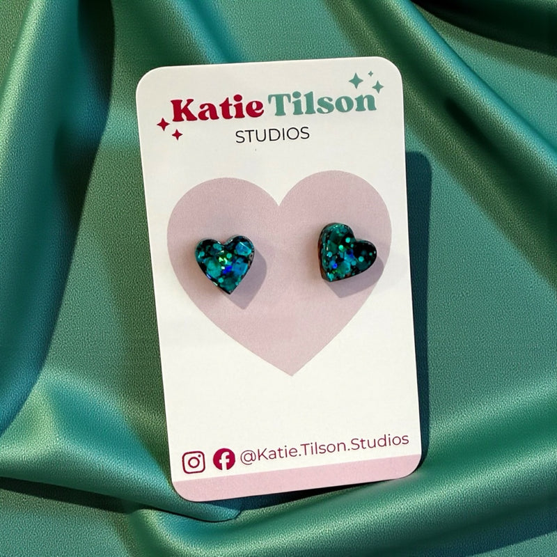Heart-shaped earrings on a Katie Tilson Studios card with social media handles.