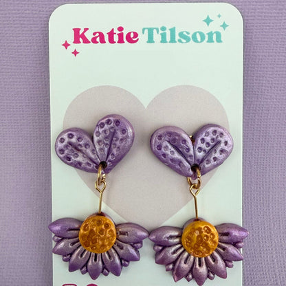 Purple and gold floral drop earrings on a Katie Tilson branded card against a purple background.