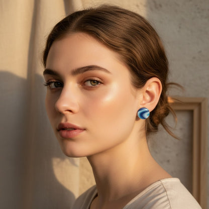 Woman wearing Australian handmade blue round stud earrings with a neutral background behind her.