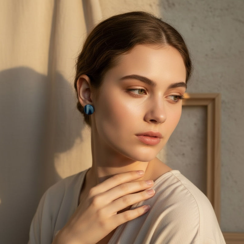 Woman wearing wavelength blue handmade stud earrings and a light-colored dress with a neutral background